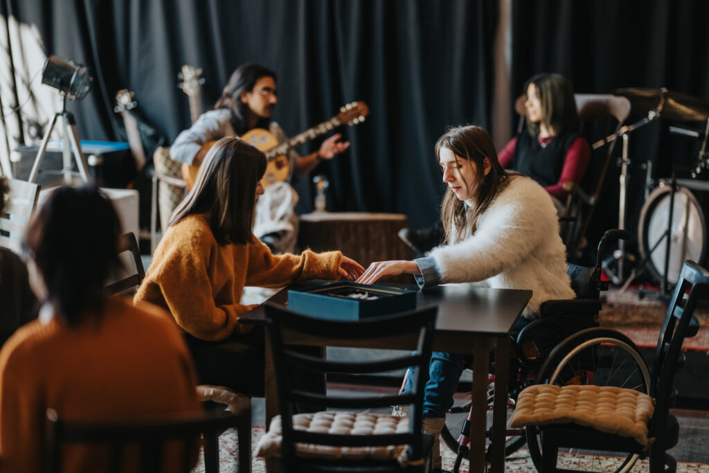 Students playing a board game while a guitarist performs in a casual rehearsal space